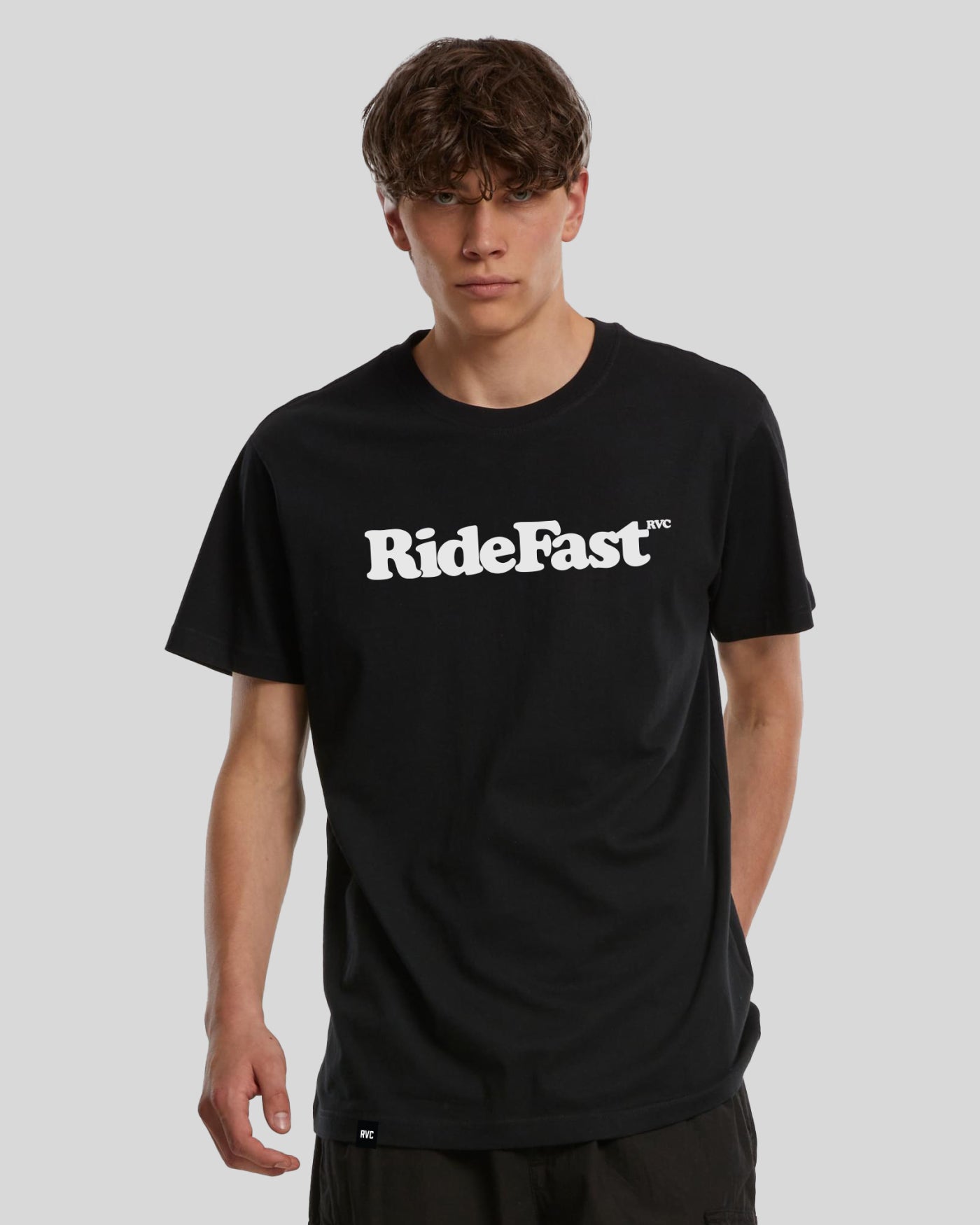 Model trägt schwarzes RVC T-Shirt aus 100 % Baumwolle, weißer »RideFast™«-Frontprint, 200 g/m², langer Regular Fit; gewebtes RVC-Label am Saum.